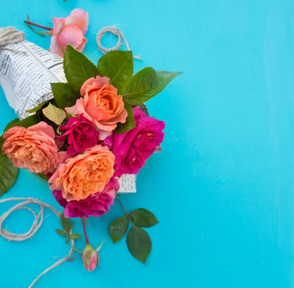 Verse roze en Oranje Rozen in papieren omslag tegenover blauwe achtergrond — Stockfoto