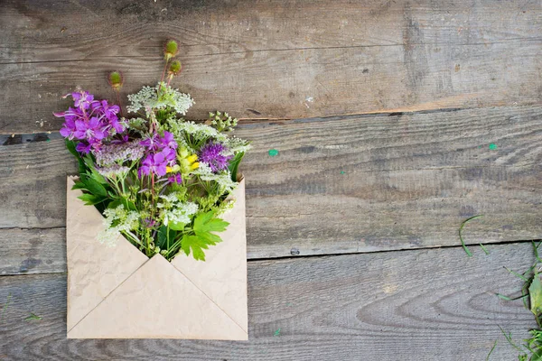 Flores de campo selvagem em envelope de papel artesanal sobre backgroun de madeira — Fotografia de Stock