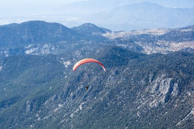 KEMER, TURKEY - 22 Ekim 2017: Türkiye 'nin Antalya ilindeki Türk Rivierası' nda bir sahil beldesi olan Kemer yakınlarındaki dağların üzerinden uçan paraglider