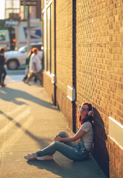 Ragazza con le cuffie vicino al muro — Foto Stock