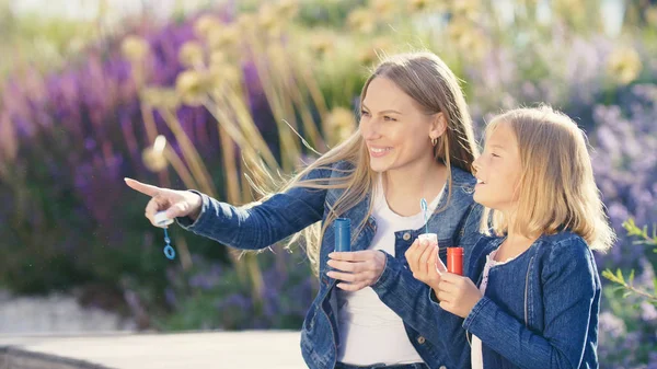 Happy mother and daughter with soap bubbles — Stock Photo, Image