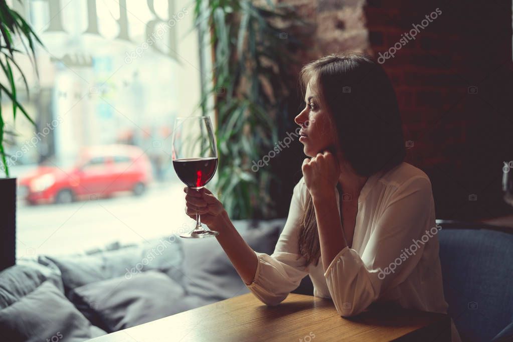 Young girl with a glass of wine in a restaurant