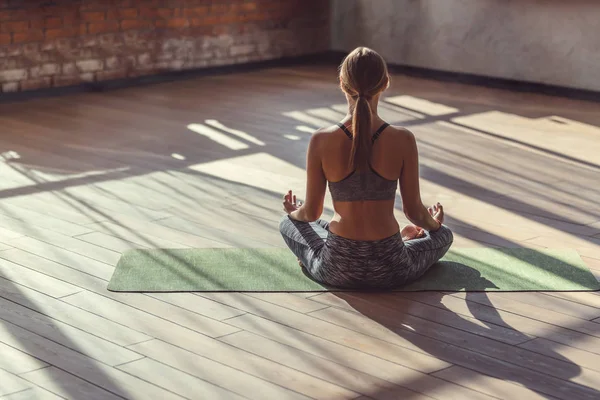 Ung kvinna i lotus pose inomhus — Stockfoto