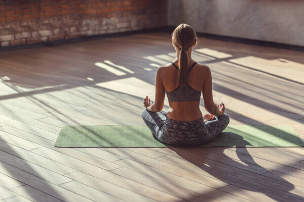 Young woman in lotus pose indoors