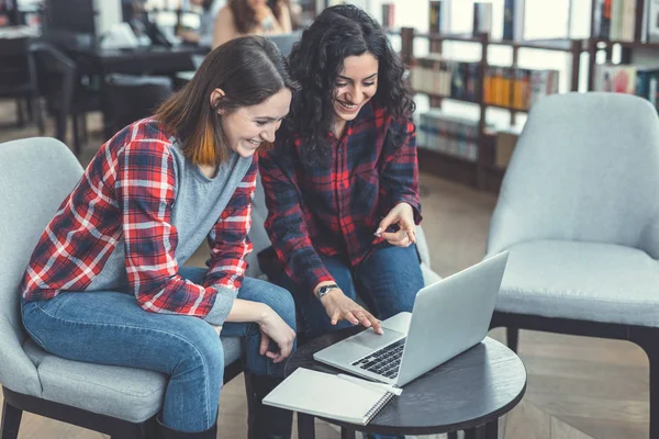 Chicas jóvenes con ordenador portátil en una librería —  Fotos de Stock