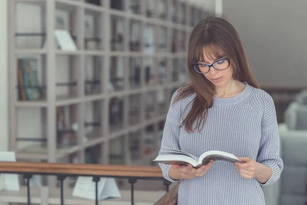 Mladá dívka čtení knihy v knihovně — Stock fotografie