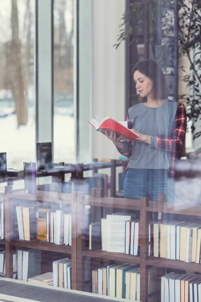 Молодая девушка читает книгу в помещении — стоковое фото