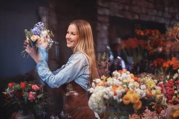 Fiorista sorridente con fiori in un negozio — Foto Stock