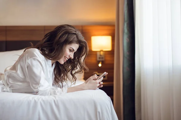 Lachende jonge vrouw met een telefoon binnenshuis — Stockfoto