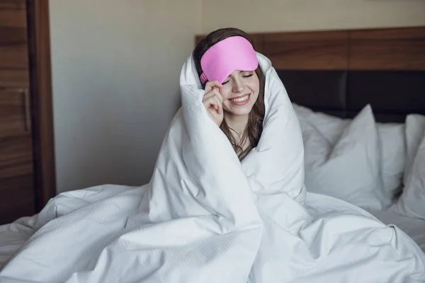 Chica joven con una máscara para dormir en la cama — Foto de Stock