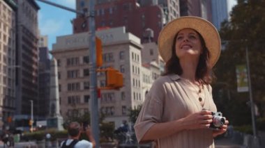 Yazın New York 'ta elinde retro kamerayla gülümseyen bir kız.