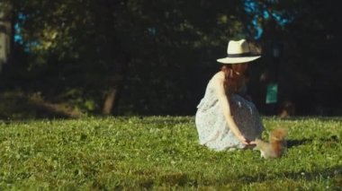 Gülümseyen kadın Central Park 'taki çimlerde bir sincabı besliyor.