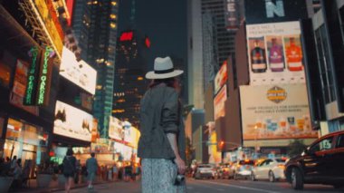 Geceleri New York 'ta elinde retro kamera olan genç bir kadın.