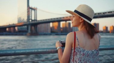 Manhattan Köprüsü 'nde elinde retro kamera olan genç bir kadın.