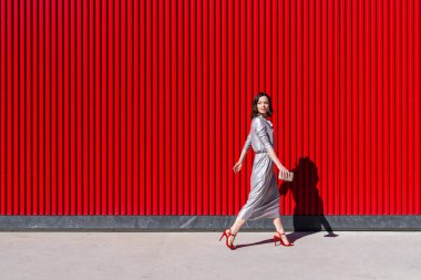 Dışarıdaki kırmızı duvara karşı çekici bir kadın.