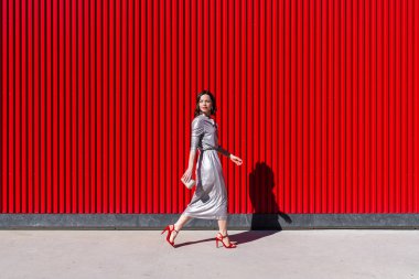 Genç ve çekici bir kadın kırmızı duvara yaslanmış.