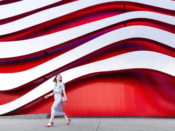 Mujer atractiva en vestido en la pared roja —  Fotos de Stock