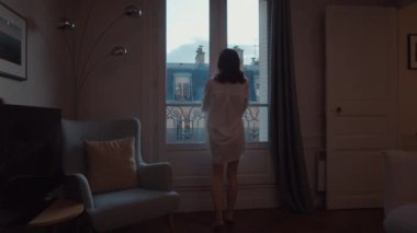 Attractive girl goes out on a balcony in Paris