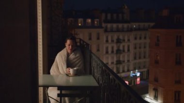 Young woman with a cup of tea in Paris at night