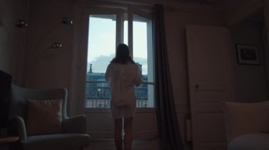 Attractive woman opening the door to the balcony 
