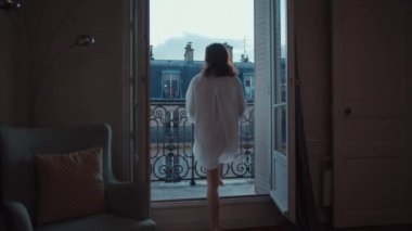 Young girl running to open balcony with a view of Paris