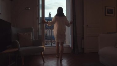 Young girl opening the door to the balcony in Paris