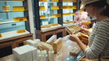 Güzel kız parfüm dükkanında hediye seçiyor.