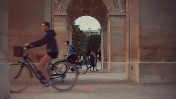 파리의 아치형을 달리는 자전거타는 사람들 — 비디오