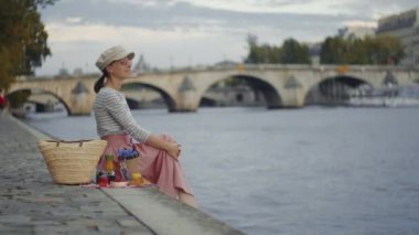 Paris 'te nehir kenarında piknik yapan çekici bir turist.