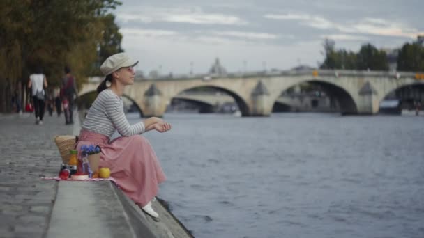 在法国塞纳河边野餐时微笑的女人 — 图库视频影像