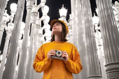 Los Angeles 'ta ünlü bir yerde elinde retro kamera olan genç bir turist.
