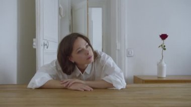 Çekici kız boş bir dairede masada uyanıyor.