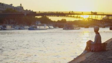 Gün batımında nehir kenarında piknik yapan genç bir turist.