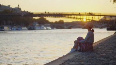 Genç turist Paris 'te nehir kenarında piknik yapıyor.