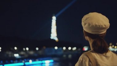 Genç turist gece Eyfel kulesine bakıyor.