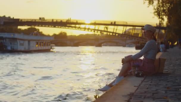 在巴黎 一个迷人的女孩在日落时在河边野餐 — 图库视频影像