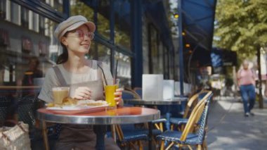 Mutlu kadın Paris, Fransa 'da bir kafede kahvaltı yapıyor.