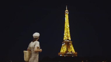 Gece Eyfel kulesinde fotoğraf çeken genç bir kız.