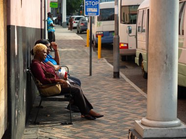 Şehirdeki otobüs durağında bekleyen bir kadın var.