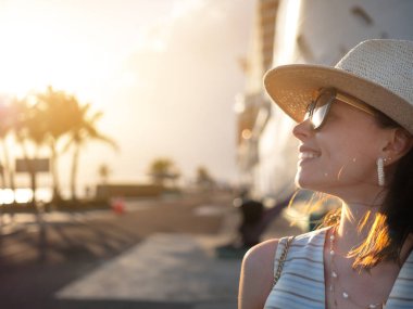 Limandaki beyaz bir geminin arka planında gülümseyen kadın.