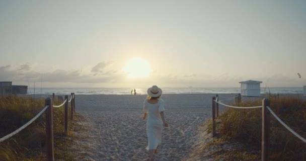 Ung kvinna i en vit klänning som springer till stranden — Stockvideo