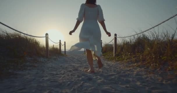 Gelukkige vrouw in een witte jurk rennen naar het strand — Stockvideo