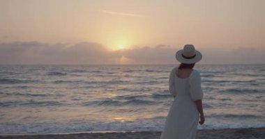 Gün batımında deniz kenarında çekici bir kadın, ağır çekimde. Siyah Sihirli Sinema Kamerasında Çekim