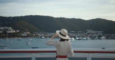 Güvertede gemilere bakan çekici bir kız.