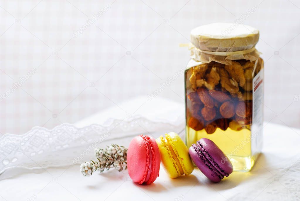 Colorful macaroons and jar of honey and nuts