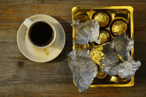 Bir fincan kahve ve çikolata tatlılar ahşap bir masa üzerinde — Stok fotoğraf