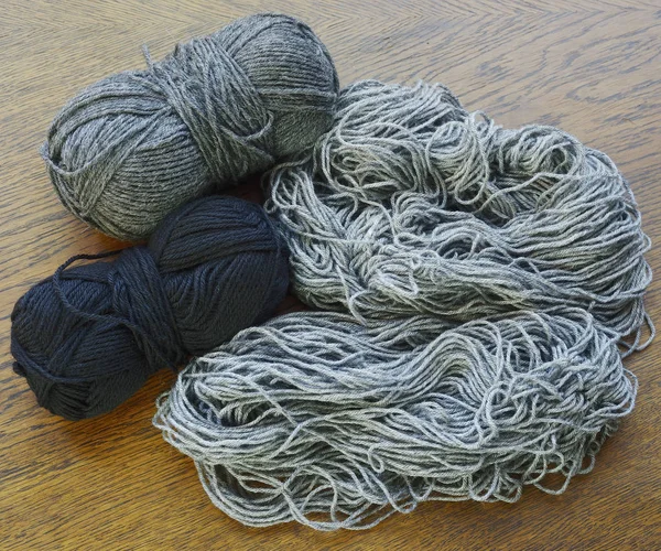 Schwarze und graue Wolle auf einer Holzoberfläche — Stockfoto