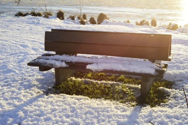 Bir karla kaplı gölün kıyısında bankta — Stok fotoğraf