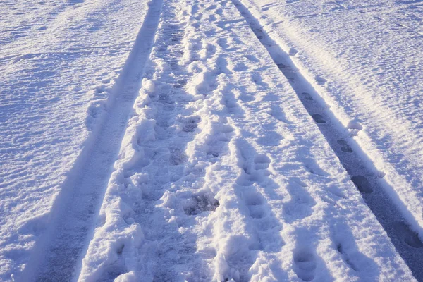 Traços das pernas e do carro na superfície nevada — Fotografia de Stock