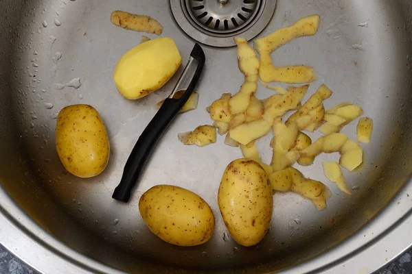 Vegetabiliska skalaren, potatis och potatis skal i diskhon — Stockfoto